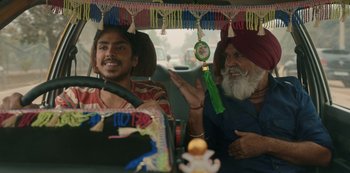 Movie still from “The White Tiger” (2021), directed by Ramin Bahrani – A man and a man in a turban sitting in a car; Medium shot, Over the shoulder angle