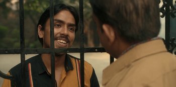 Movie still from “The White Tiger” (2021), directed by Ramin Bahrani – Two men talking to each other in front of a fence; Close Up shot, Over the shoulder angle