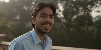Movie still from “The White Tiger” (2021), directed by Ramin Bahrani – A person wearing a blue shirt; Close Up shot, Low angle