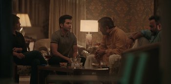 Movie still from “The White Tiger” (2021), directed by Ramin Bahrani – Two men sitting at a table talking to each other; Medium shot, Over the shoulder angle