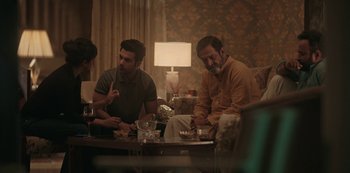Movie still from “The White Tiger” (2021), directed by Ramin Bahrani – A group of people sitting around a living room table; Medium shot, Over the shoulder angle