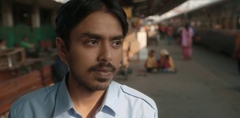 Movie still from “The White Tiger” (2021), directed by Ramin Bahrani – A person wearing a blue shirt; Close Up shot, Low angle