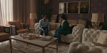 Movie still from “The White Tiger” (2021), directed by Ramin Bahrani – A man and a woman sitting on a couch in a living room; Wide shot, High angle