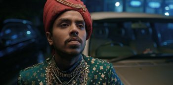 Movie still from “The White Tiger” (2021), directed by Ramin Bahrani – A man in a red turban and a green jacket; Close Up shot, Low angle