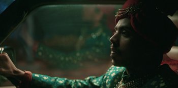 Movie still from “The White Tiger” (2021), directed by Ramin Bahrani – A person in a car wearing a red turban; Close Up shot, Low angle