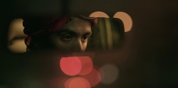 Movie still from “The White Tiger” (2021), directed by Ramin Bahrani – A man's face with a red turban on his head; Extreme Close Up shot, Low angle