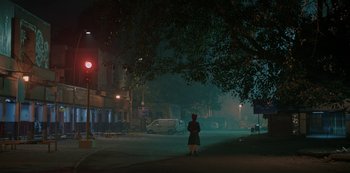 Movie still from “The White Tiger” (2021), directed by Ramin Bahrani – A person standing on the side of a road at night; Extreme Wide shot, High angle