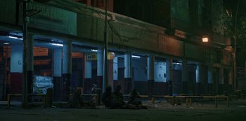 Movie still from “The White Tiger” (2021), directed by Ramin Bahrani – A group of people sitting on the side of the street; Extreme Wide shot, Low angle