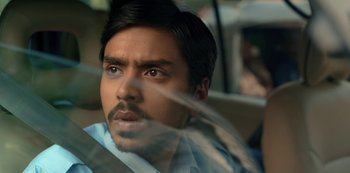 Movie still from “The White Tiger” (2021), directed by Ramin Bahrani – A person in a car looking at the camera; Close Up shot, Low angle