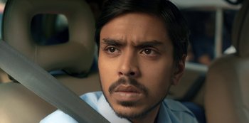 Movie still from “The White Tiger” (2021), directed by Ramin Bahrani – A person in a car wearing a seat belt; Close Up shot, Low angle