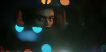Movie still from “The White Tiger” (2021), directed by Ramin Bahrani – A man looking into the camera through a window; Extreme Close Up shot, Low angle