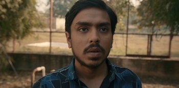 Movie still from “The White Tiger” (2021), directed by Ramin Bahrani – A person wearing a blue shirt; Close Up shot, High angle