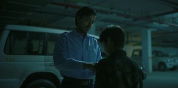 Movie still from “The White Tiger” (2021), directed by Ramin Bahrani – A man in a blue dress shirt and a man in a black shirt; Medium shot, Low angle