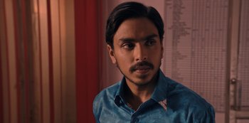 Movie still from “The White Tiger” (2021), directed by Ramin Bahrani – A person wearing a blue shirt; Close Up shot, Over the shoulder angle