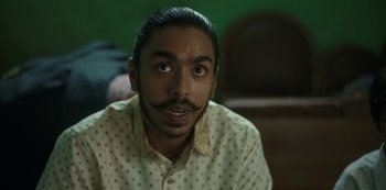 Movie still from “The White Tiger” (2021), directed by Ramin Bahrani – A person with a mustache wearing a shirt; Close Up shot, Low angle