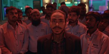 Movie still from “The White Tiger” (2021), directed by Ramin Bahrani – A group of men standing in a room; Medium shot, Low angle