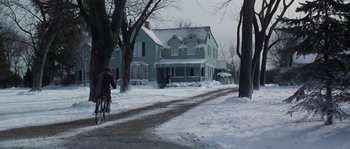 Movie still from “Road to Perdition” (2002), directed by Sam Mendes – A person riding a bike on a snow covered street; Extreme Wide shot, Low angle