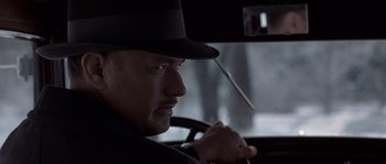 Movie still from “Road to Perdition” (2002), directed by Sam Mendes – A man wearing a hat sitting in the driver's seat of a car; Close Up shot, Low angle