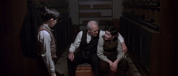Movie still from “Road to Perdition” (2002), directed by Sam Mendes – A group of people sitting on top of a wooden box; Medium shot, Over the shoulder angle