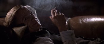 Movie still from “Road to Perdition” (2002), directed by Sam Mendes – A man smoking a cigarette while holding a cell phone in his hand; Close Up shot, Low angle