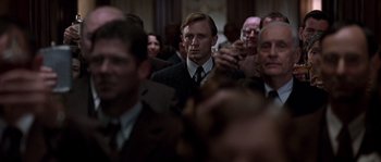 Movie still from “Road to Perdition” (2002), directed by Sam Mendes – A group of men in suits and ties standing in a room; Medium shot, Low angle