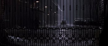 Movie still from “Road to Perdition” (2002), directed by Sam Mendes – A car is driving down the street in the rain; Extreme Wide shot, Low angle