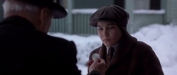 Movie still from “Road to Perdition” (2002), directed by Sam Mendes – A young man wearing a hat holding a coin in his hand; Close Up shot, Over the shoulder angle