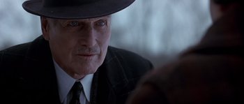 Movie still from “Road to Perdition” (2002), directed by Sam Mendes – An older man wearing a hat and a suit; Close Up shot, Over the shoulder angle