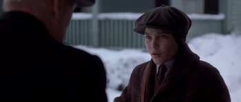 Movie still from “Road to Perdition” (2002), directed by Sam Mendes – A young boy wearing a hat and a suit; Close Up shot, Over the shoulder angle