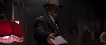 Movie still from “Road to Perdition” (2002), directed by Sam Mendes – A man wearing a hat and holding a piece of paper in his hand; Close Up shot, Low angle