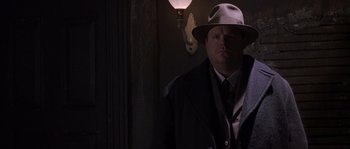 Movie still from “Road to Perdition” (2002), directed by Sam Mendes – A man wearing a hat and a coat; Close Up shot, Over the shoulder angle