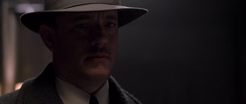 Movie still from “Road to Perdition” (2002), directed by Sam Mendes – A person wearing a hat and a suit; Close Up shot, Over the shoulder angle