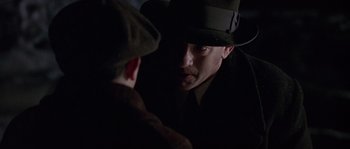 Movie still from “Road to Perdition” (2002), directed by Sam Mendes – A man wearing a hat looking into a mirror; Close Up shot, Over the shoulder angle