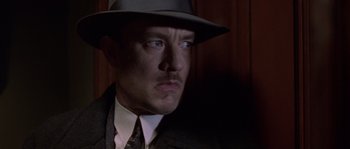 Movie still from “Road to Perdition” (2002), directed by Sam Mendes – A person wearing a suit and a hat; Close Up shot, Low angle