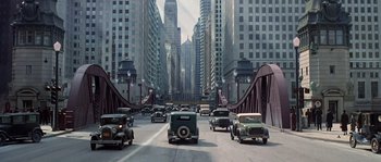 Movie still from “Road to Perdition” (2002), directed by Sam Mendes – An image of a street scene with many cars on the road; Extreme Wide shot, High angle