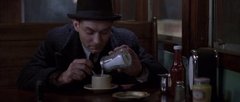 Movie still from “Road to Perdition” (2002), directed by Sam Mendes – A man in a top hat pouring a drink into a cup; Close Up shot, High angle