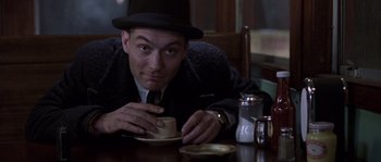 Movie still from “Road to Perdition” (2002), directed by Sam Mendes – A man sitting at a table with a plate of food; Medium shot, High angle