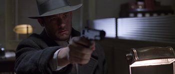 Movie still from “Road to Perdition” (2002), directed by Sam Mendes – A man holding a gun while wearing a hat; Close Up shot, Low angle