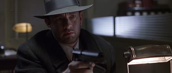 Movie still from “Road to Perdition” (2002), directed by Sam Mendes – A man in a hat holding a gun in his hand; Close Up shot, Low angle