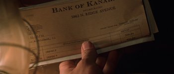 Movie still from “Road to Perdition” (2002), directed by Sam Mendes – A hand is holding a bank of kanakee check; Extreme Close Up shot, High angle