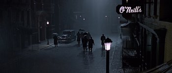 Movie still from “Road to Perdition” (2002), directed by Sam Mendes – A group of people walking down a street at night; Extreme Wide shot, High angle
