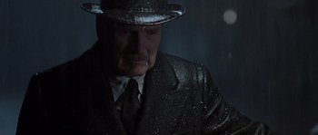 Movie still from “Road to Perdition” (2002), directed by Sam Mendes – An older man in a suit and hat in the rain; Close Up shot, Low angle