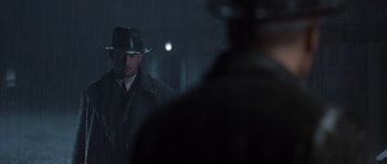 Movie still from “Road to Perdition” (2002), directed by Sam Mendes – A man wearing a hat and a coat; Medium shot, Over the shoulder angle