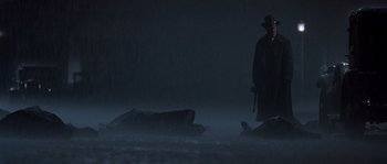 Movie still from “Road to Perdition” (2002), directed by Sam Mendes – A man standing in the dark next to a dead body; Wide shot, Low angle