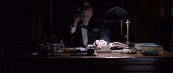 Movie still from “Road to Perdition” (2002), directed by Sam Mendes – A man sitting at a desk talking on the phone; Medium shot, Low angle