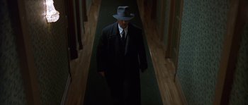Movie still from “Road to Perdition” (2002), directed by Sam Mendes – A man in a suit and hat walking down a hall way; Wide shot, Low angle