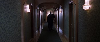 Movie still from “Road to Perdition” (2002), directed by Sam Mendes – A man walking down a long hallway in a hotel; Wide shot, High angle