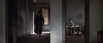 Movie still from “Road to Perdition” (2002), directed by Sam Mendes – A man in a black coat and a man in a black hat; Wide shot, Low angle