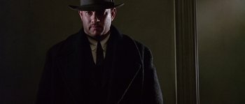 Movie still from “Road to Perdition” (2002), directed by Sam Mendes – A man wearing a hat and a coat; Close Up shot, Low angle