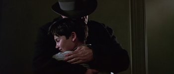 Movie still from “Road to Perdition” (2002), directed by Sam Mendes – A man in a hat is hugging a young man; Close Up shot, Low angle